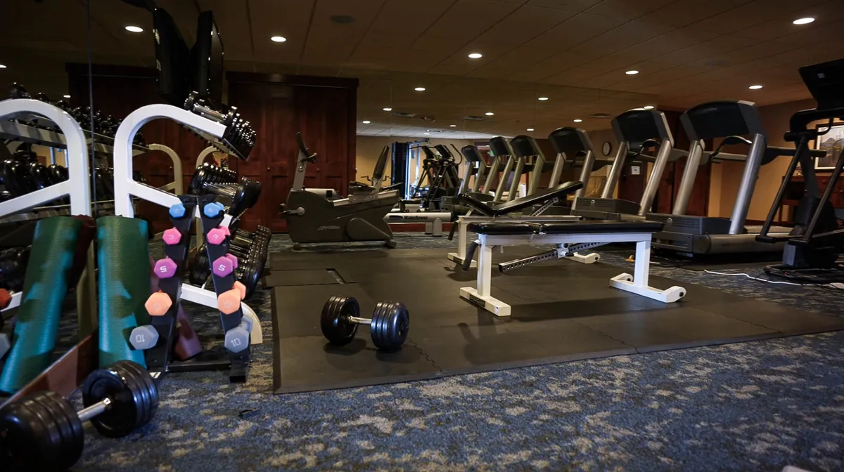 A well-equipped fitness room with dumbbells, treadmills, a weight bench, and exercise mats. The space is designed for personal workouts or group fitness activities, providing guests with opportunities to stay active during their stay.